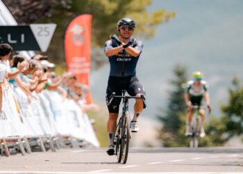 Ciclista cruza la meta celebrando con los brazos en la forma de X ante el público en Sabiñánigo