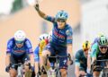 Tim Merlier celebra su victoria alzando el brazo en un sprint masivo