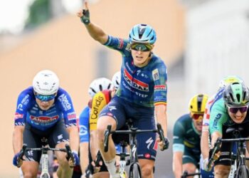 Tim Merlier celebra su victoria alzando el brazo en un sprint masivo