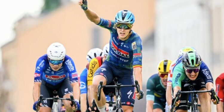 Tim Merlier celebra su victoria alzando el brazo en un sprint masivo