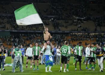 Afición del Real Betis con una bandera verdiblanca en el estadio.